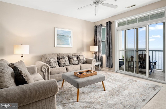 living room with ceiling fan and a water view