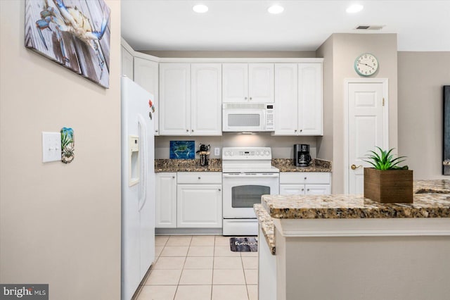 kitchen featuring light tile flooring, white appliances, dark stone countertops, and white cabinets