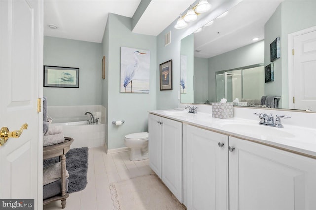 bathroom featuring double vanity, a relaxing tiled bath, tile floors, and toilet