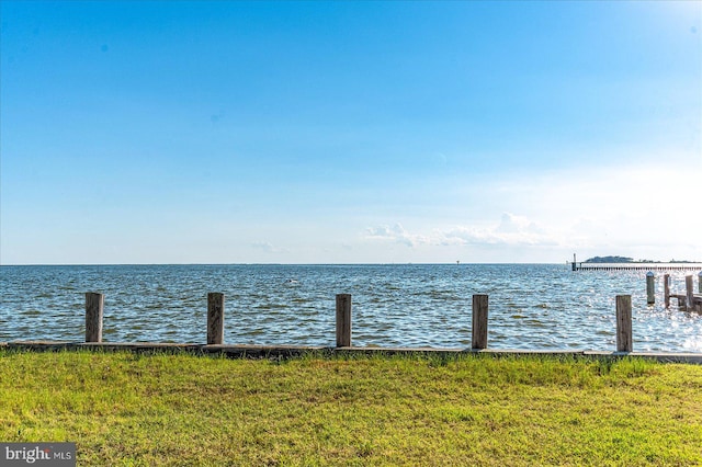 view of dock with a water view and a yard