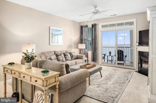 living room featuring ceiling fan, a water view, and light colored carpet