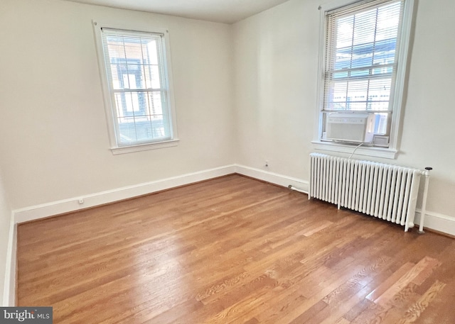 empty room with radiator, hardwood / wood-style floors, and cooling unit