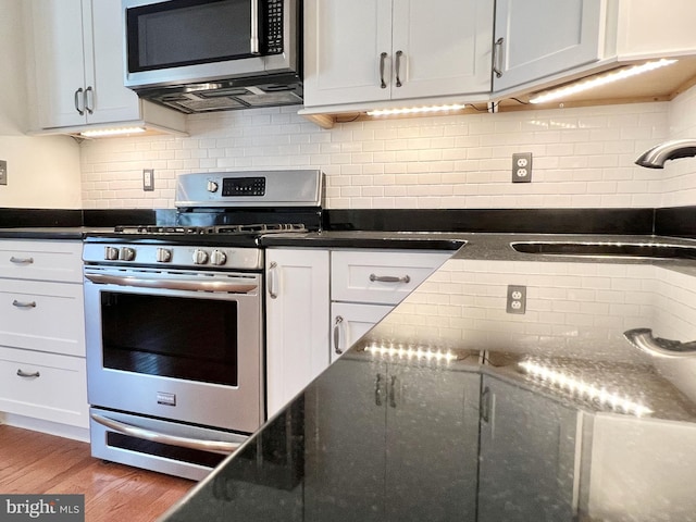 kitchen featuring sink, stainless steel appliances, backsplash, wood-type flooring, and white cabinets