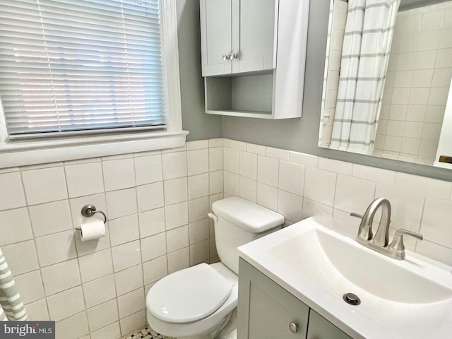 bathroom with vanity, toilet, and tile walls