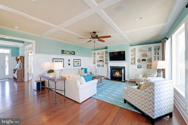 living room featuring ceiling fan, built in shelves, coffered ceiling, and dark hardwood / wood-style floors