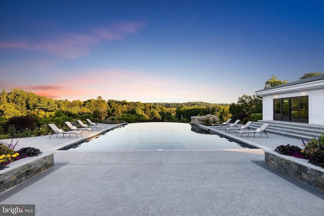 pool at dusk featuring a patio