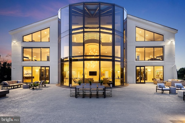 back house at dusk featuring a patio area and an outdoor living space