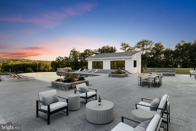 patio terrace at dusk with an outdoor living space with a fireplace