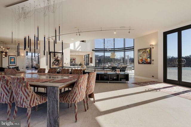 dining area with tile floors, a healthy amount of sunlight, track lighting, and a chandelier