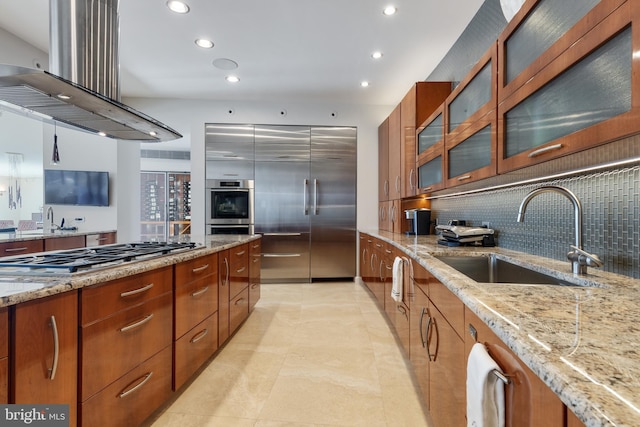 kitchen with ventilation hood, tasteful backsplash, appliances with stainless steel finishes, sink, and light stone counters