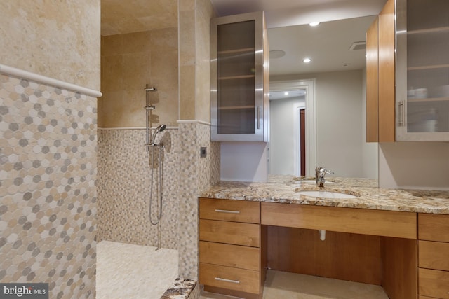 bathroom with a tile shower and large vanity