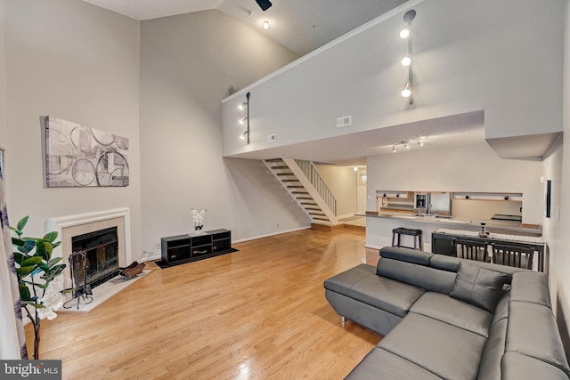 living room with high vaulted ceiling, light hardwood / wood-style floors, and track lighting