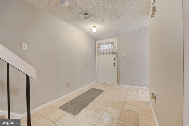 entrance foyer with light tile floors and a textured ceiling