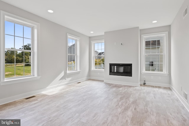 unfurnished living room featuring plenty of natural light and light hardwood / wood-style floors