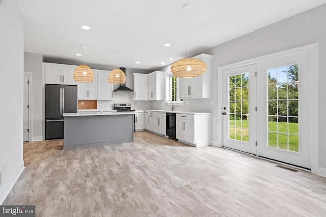 kitchen with plenty of natural light, pendant lighting, stainless steel appliances, and light hardwood / wood-style floors