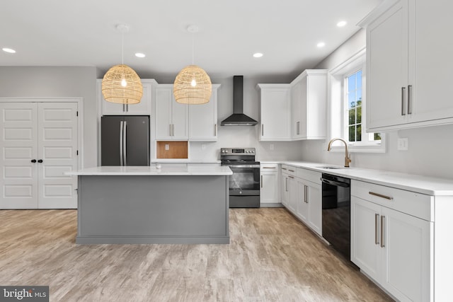 kitchen with light hardwood / wood-style flooring, decorative light fixtures, wall chimney exhaust hood, and stainless steel appliances