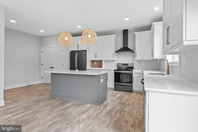 kitchen with sink, appliances with stainless steel finishes, light hardwood / wood-style flooring, wall chimney exhaust hood, and white cabinetry