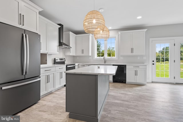 kitchen featuring appliances with stainless steel finishes, light hardwood / wood-style flooring, white cabinets, wall chimney exhaust hood, and pendant lighting