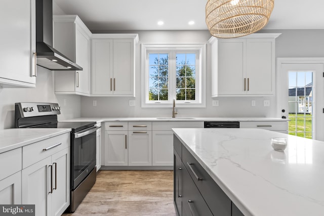 kitchen with stainless steel electric range, sink, white cabinets, light hardwood / wood-style floors, and wall chimney exhaust hood