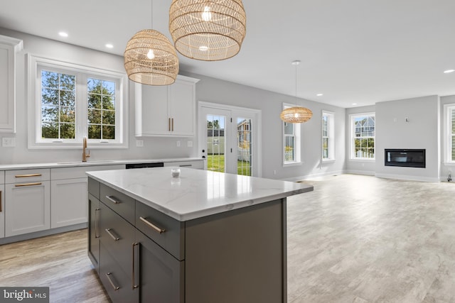 kitchen with a kitchen island, decorative light fixtures, light hardwood / wood-style flooring, white cabinetry, and sink