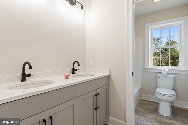 full bathroom featuring double sink vanity, toilet,  shower combination, and wood-type flooring