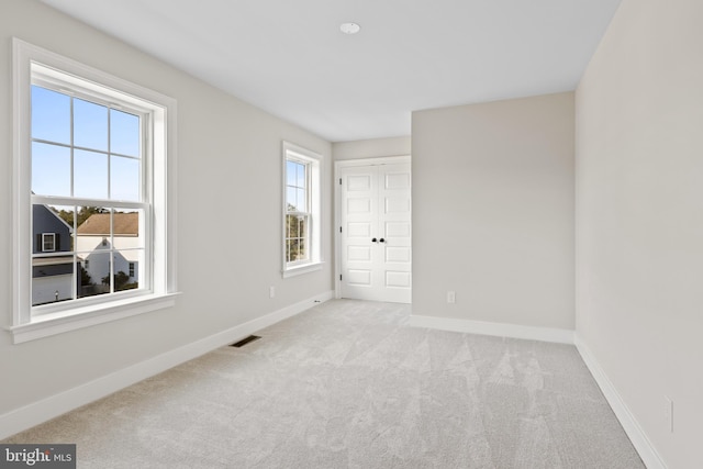 unfurnished room featuring a healthy amount of sunlight and light colored carpet