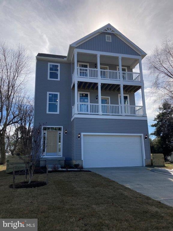 view of front of property featuring a balcony, a front yard, and a garage