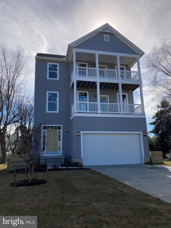 view of front of property featuring a balcony, a front lawn, and a garage