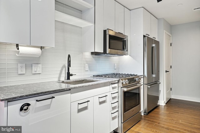 kitchen with white cabinetry, wood-type flooring, stainless steel appliances, stone counters, and backsplash