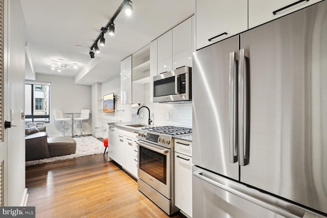 kitchen with decorative backsplash, appliances with stainless steel finishes, light hardwood / wood-style floors, and white cabinetry