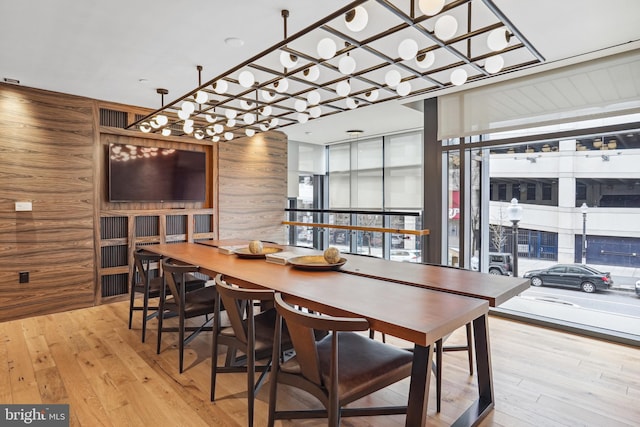 dining area with wooden walls, light wood-type flooring, and plenty of natural light