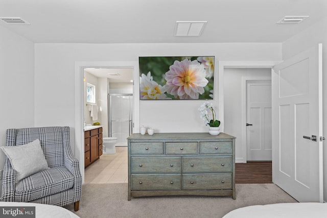 bedroom featuring ensuite bath and light colored carpet