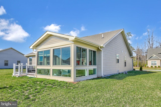 back of property with a sunroom and a yard