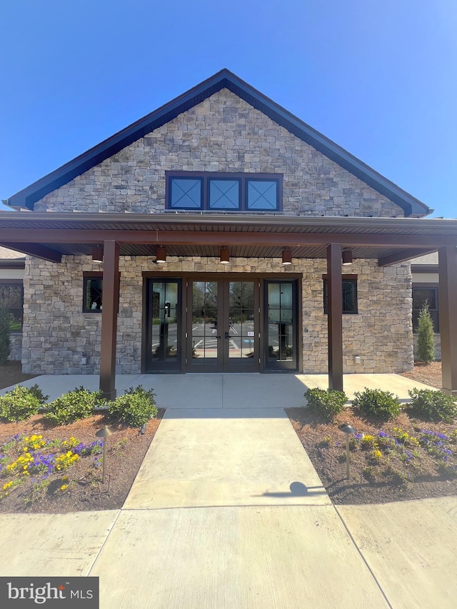 rear view of property featuring covered porch and french doors