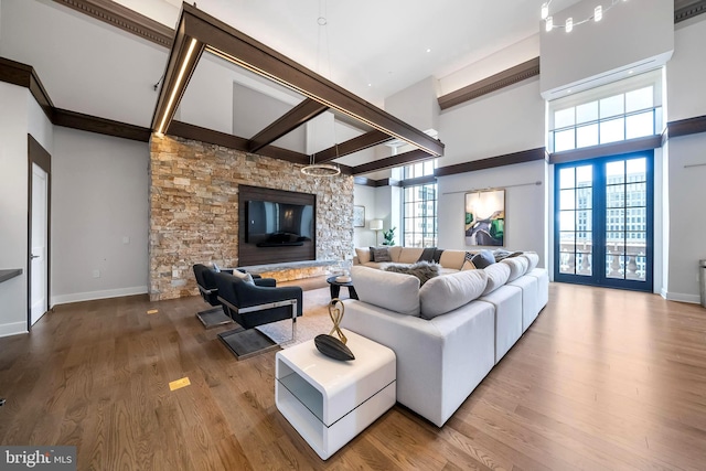 living room with beam ceiling, a fireplace, wood-type flooring, and french doors