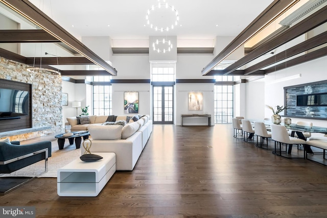 living room featuring an inviting chandelier, dark wood-type flooring, and a towering ceiling