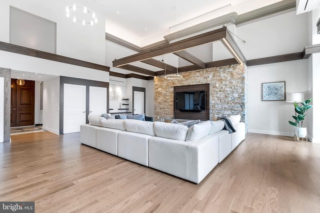 living room featuring beam ceiling, a fireplace, and light hardwood / wood-style floors