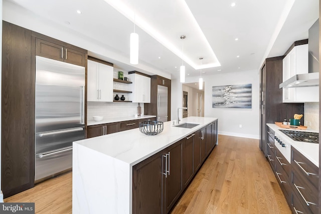 kitchen with backsplash, stainless steel appliances, decorative light fixtures, and light hardwood / wood-style floors