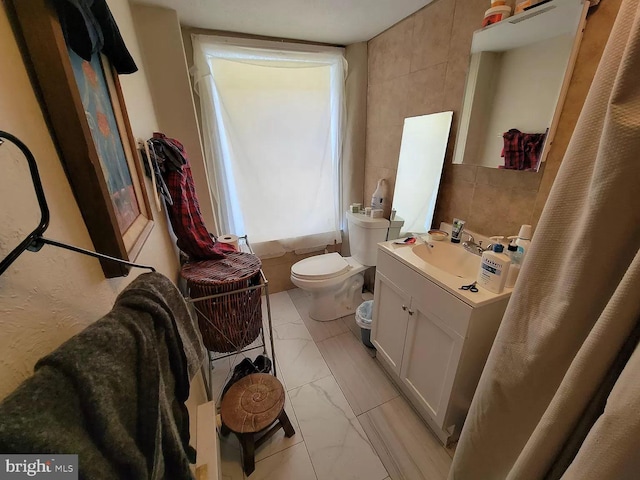 bathroom with tile walls, tile floors, toilet, and vanity