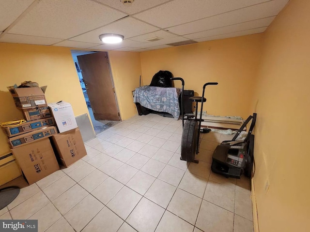 exercise area featuring light tile floors and a drop ceiling