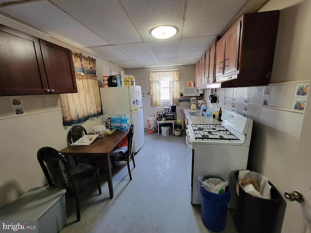 kitchen featuring sink, white appliances, and a drop ceiling