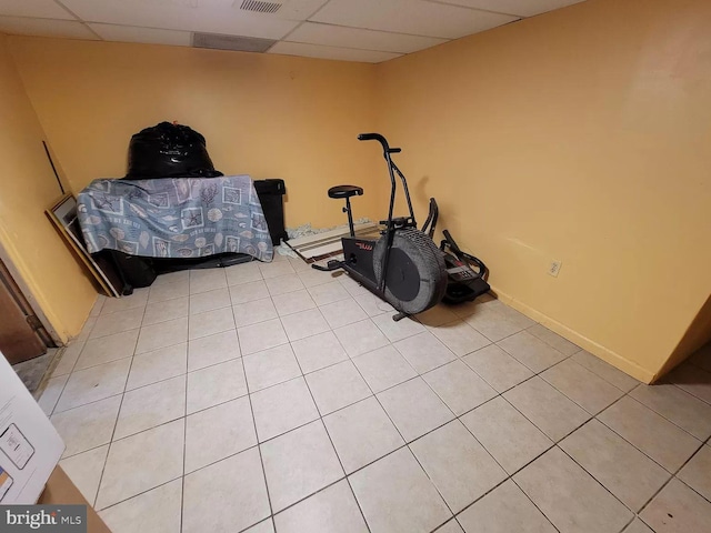 exercise area featuring a paneled ceiling and light tile floors