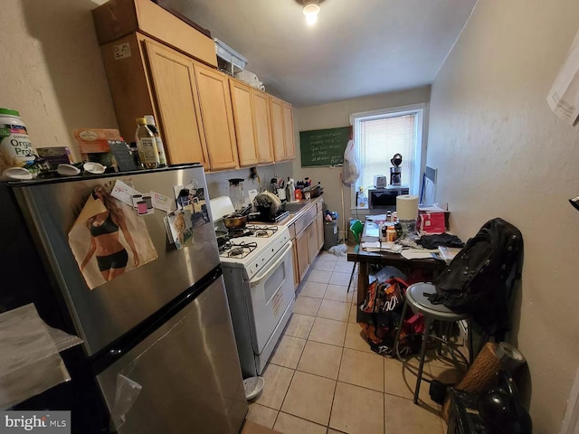 kitchen featuring light brown cabinetry, light tile floors, stainless steel refrigerator, and gas range gas stove