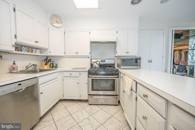 kitchen featuring sink, white cabinets, stainless steel appliances, and ornamental molding