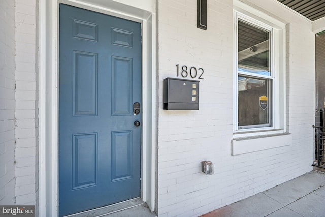 doorway to property featuring brick siding and covered porch