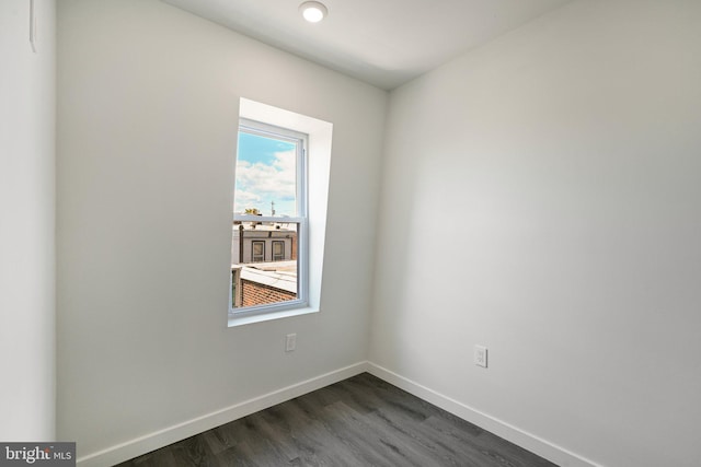 unfurnished room with baseboards and dark wood-style flooring