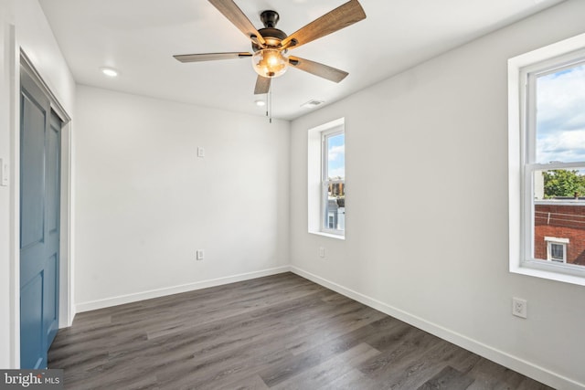 unfurnished bedroom featuring multiple windows, baseboards, and dark wood-style flooring