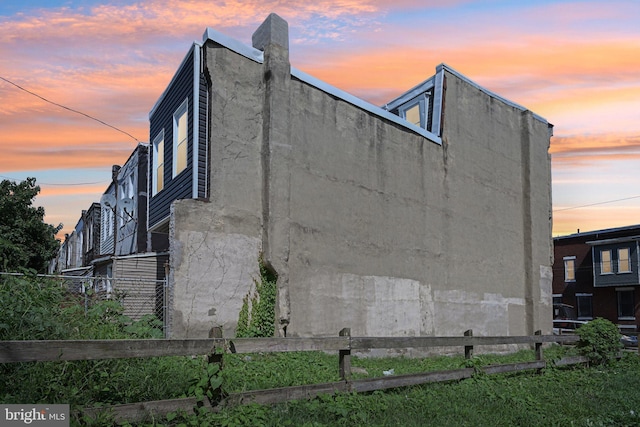 property exterior at dusk with stucco siding and fence