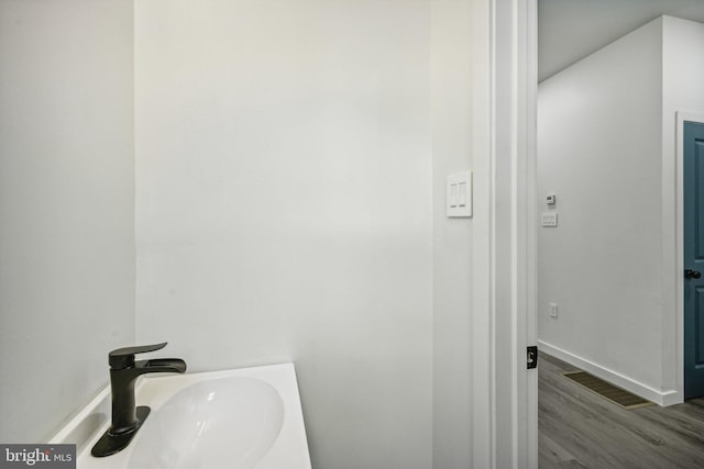 bathroom with visible vents, wood finished floors, baseboards, and a sink