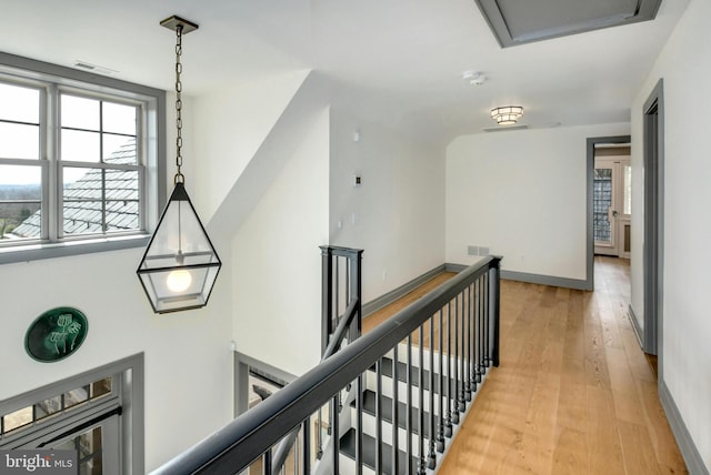 corridor with visible vents, light wood finished floors, an upstairs landing, and baseboards